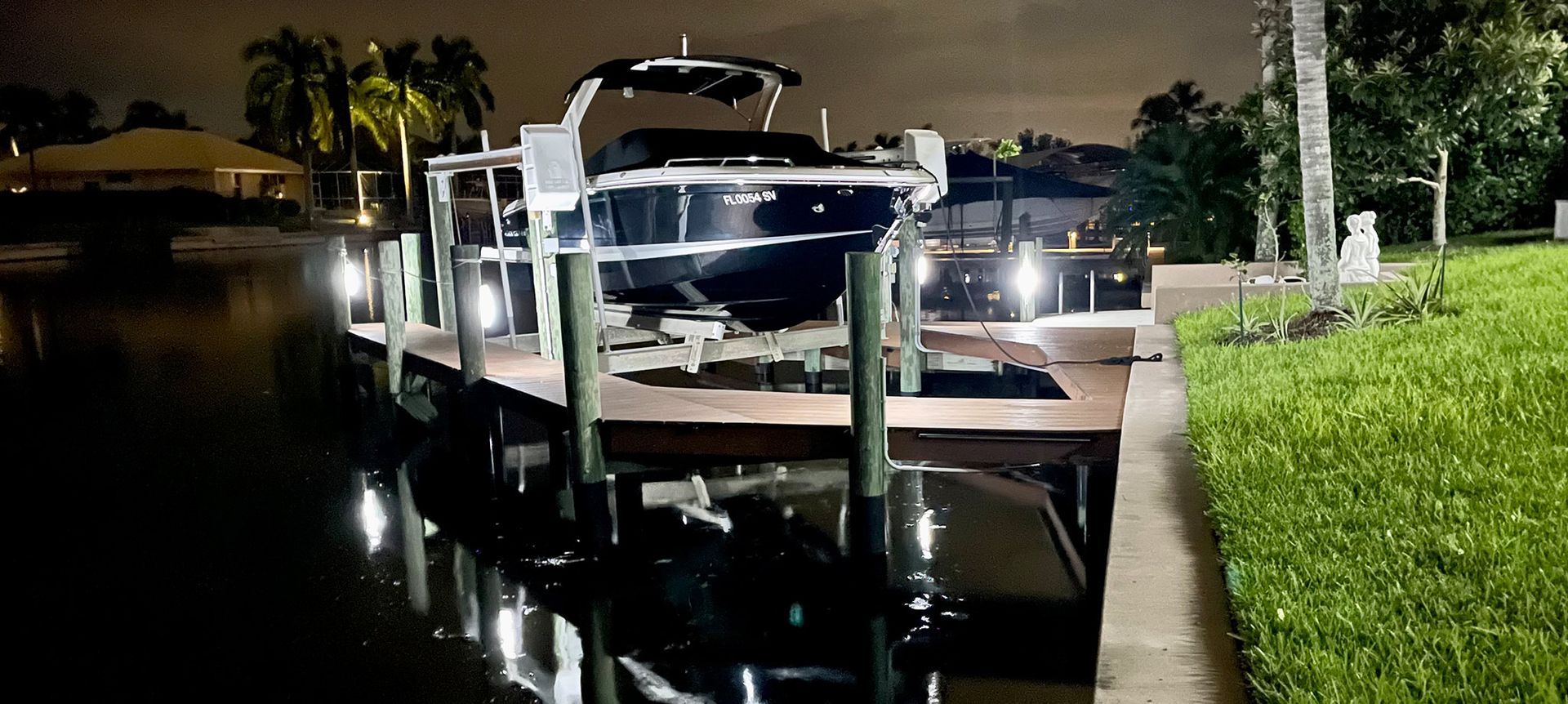 Indoor pool at night with jacuzzi, lounge chairs, and overhead lights.