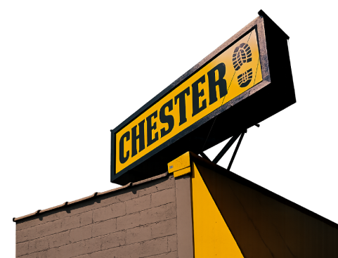Sign for Chester, a shoe store, with a footprint symbol, atop a yellow and brown building.