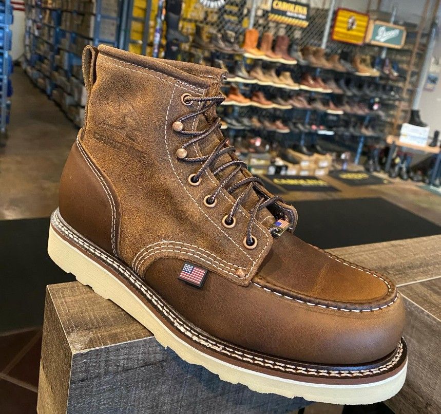 Brown work boot with white sole, on display in a shoe store.