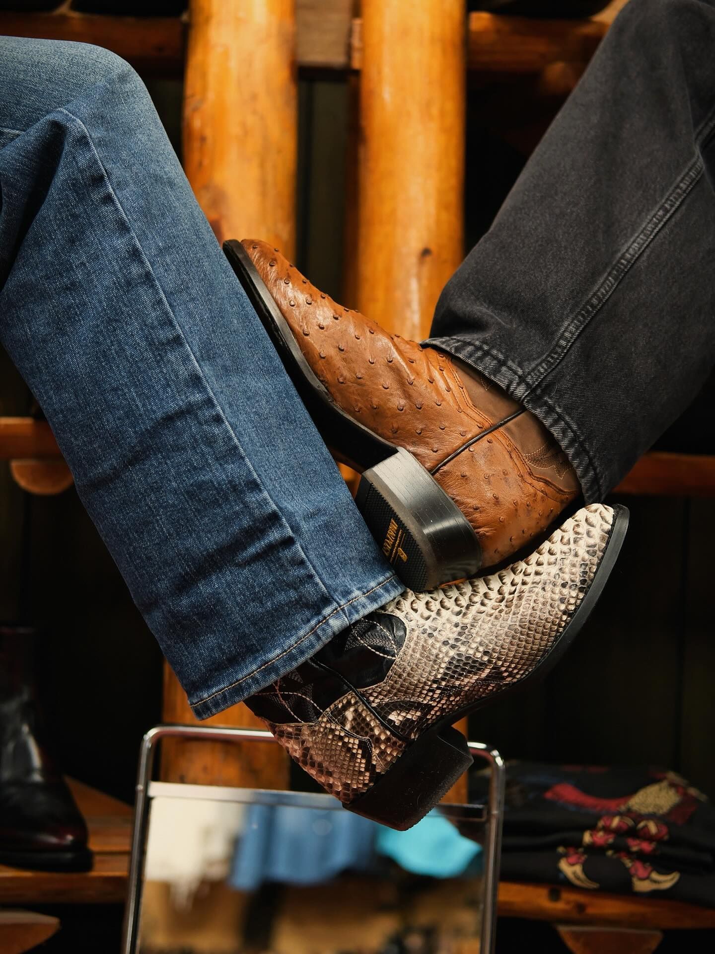 Two pairs of cowboy boots, one blue jeans and one black jeans, crossed over each other.