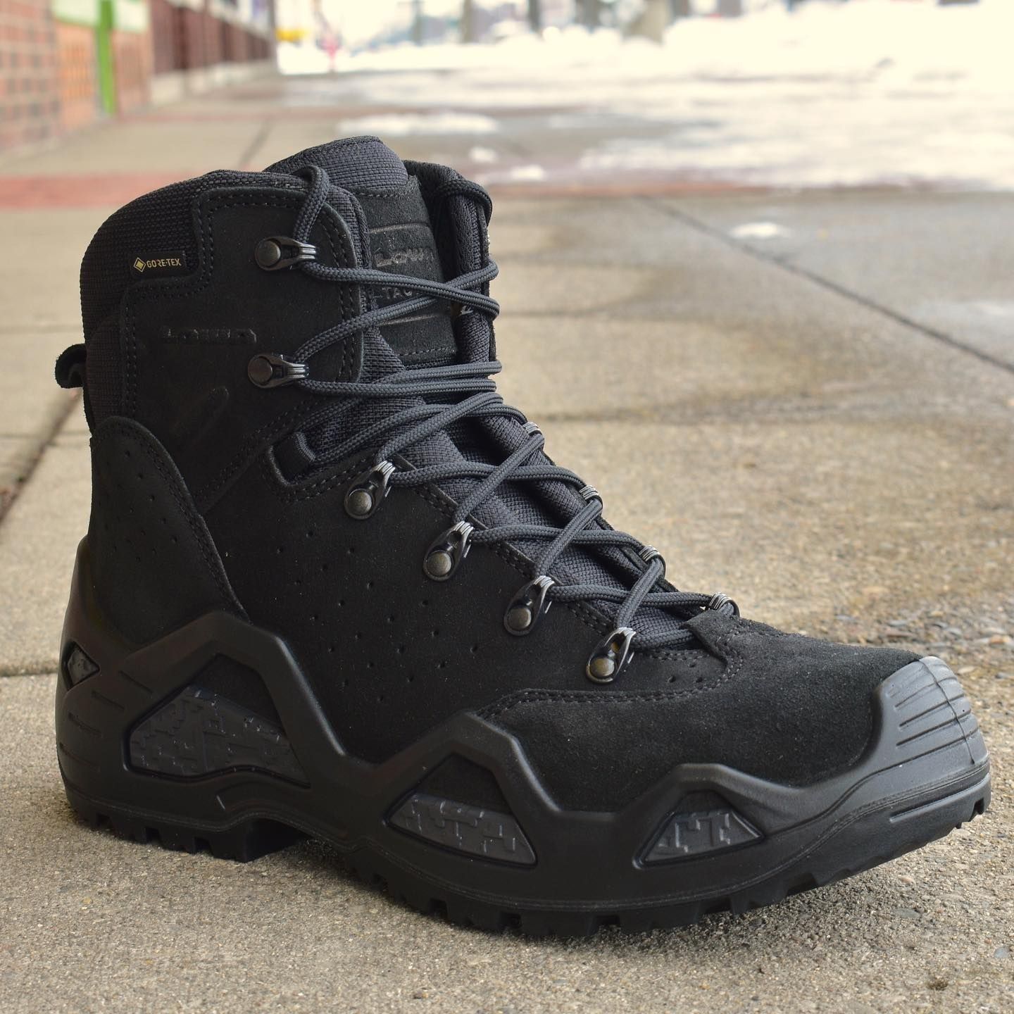 Black tactical boot on a sidewalk.