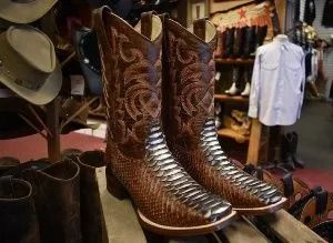 Pair of brown leather cowboy boots with decorative stitching and snakeskin pattern.