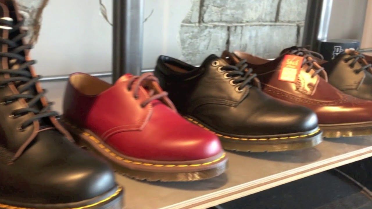 Row of Dr. Martens shoes in various colors: red, black, and brown with yellow stitching and laces.
