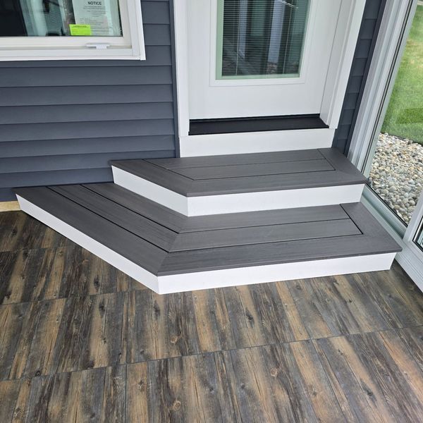 Gray composite deck steps with white trim lead to a white door.