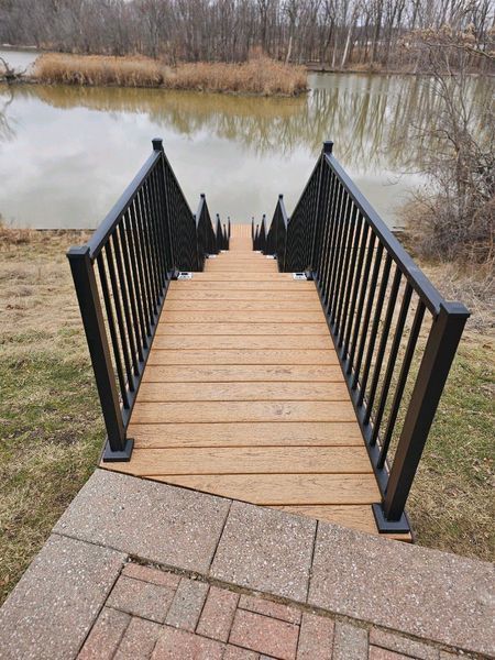 Wooden steps with black railing leading down to a body of water.