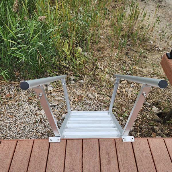 Aluminum dock steps with handrails leading down to water.