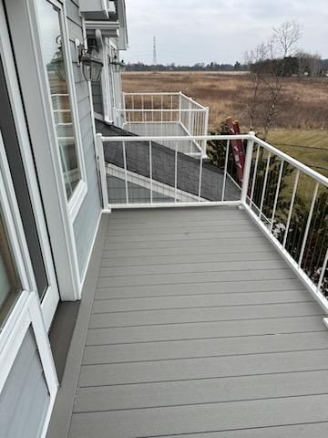 Gray composite deck with white railing, overlooking a field.