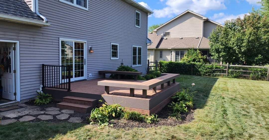 Backyard deck with dark brown railing and steps, built-in planter, and gray siding on the house.