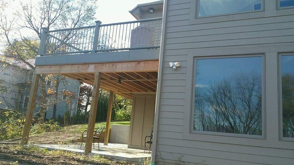 A two-story deck on the side of a house, with wooden railing.
