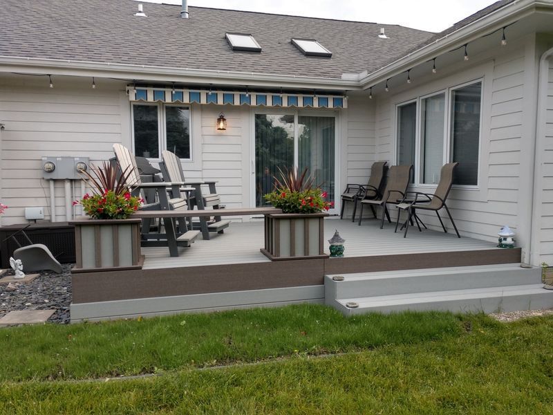 Backyard deck with planters, seating, and an awning.