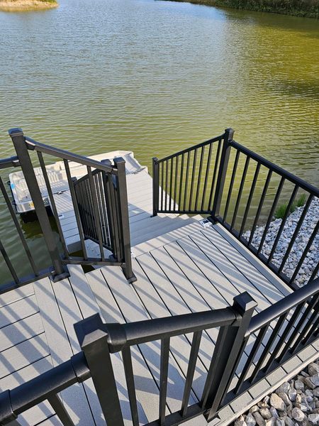 Stairway and deck with black railing leading into water. Grey composite decking.