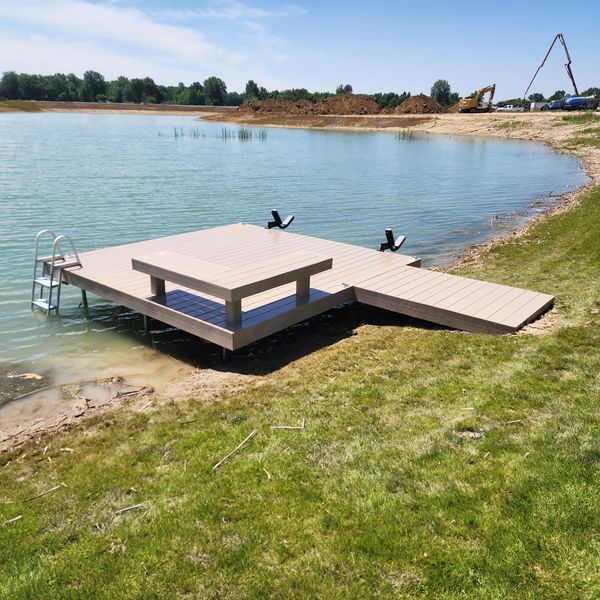 Dock extending into a lake with a table, ladder, and ramp for water access.