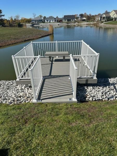 Floating picnic area with white railing, gray deck, and picnic table on a pond.