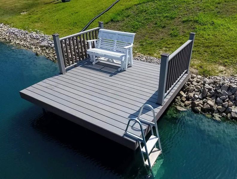 Gray composite dock with white bench and ladder in a body of water.