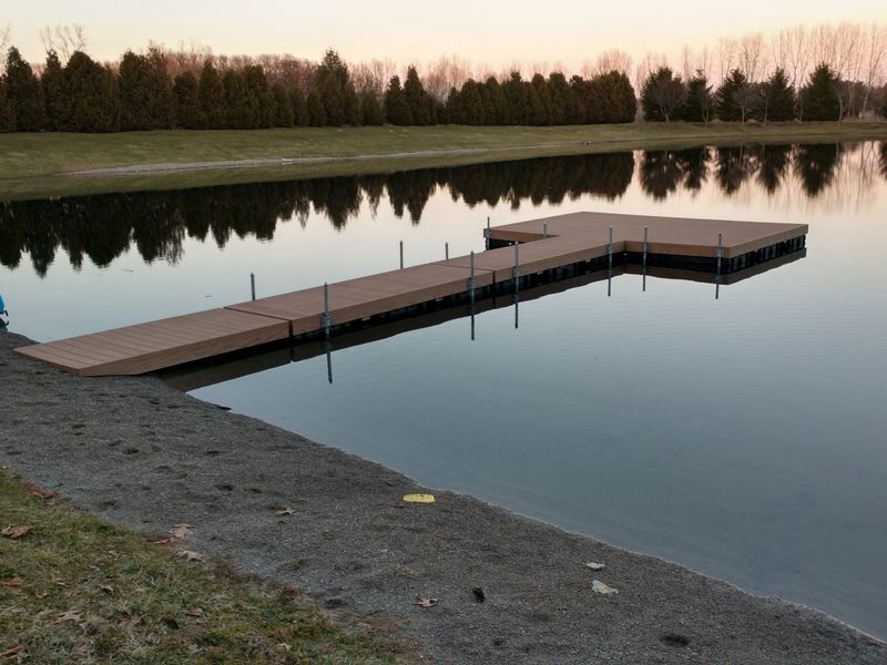 Dock extending into calm water, with reflection of trees and sky.