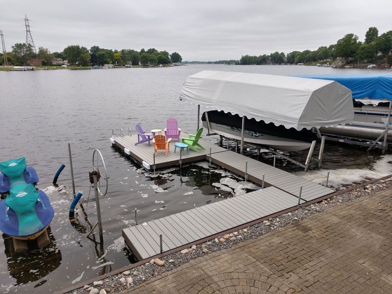 Dock with boat lift, chairs, and canopy on a lake. Overcast day.