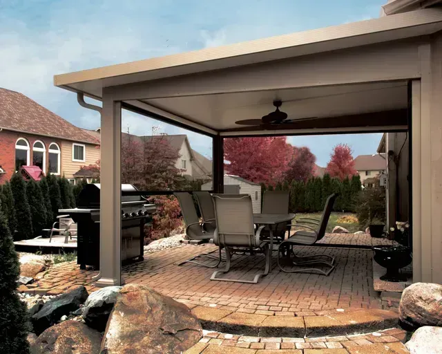 Covered patio with dining set, grill, and retractable screens, in a backyard setting.