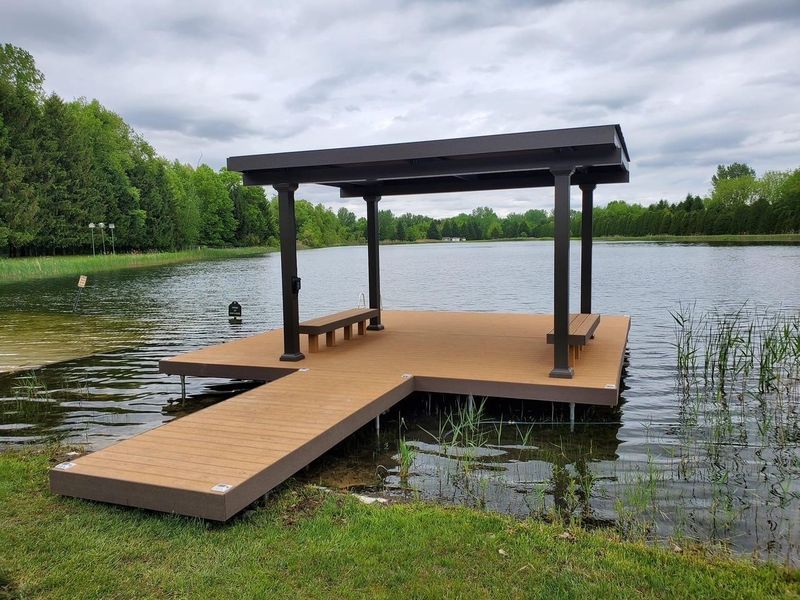 Brown dock with a covered seating area on a lake.