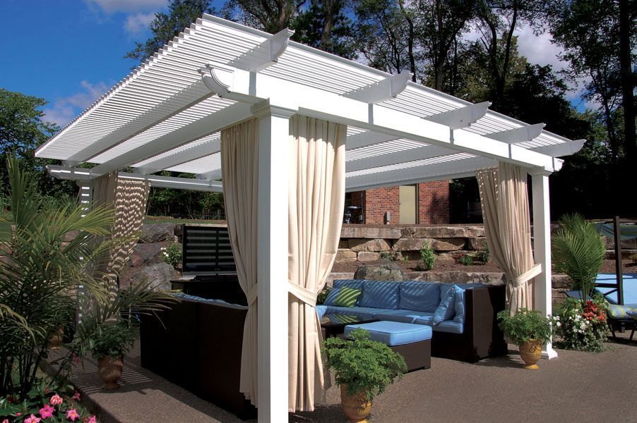 White pergola with beige curtains over outdoor seating.