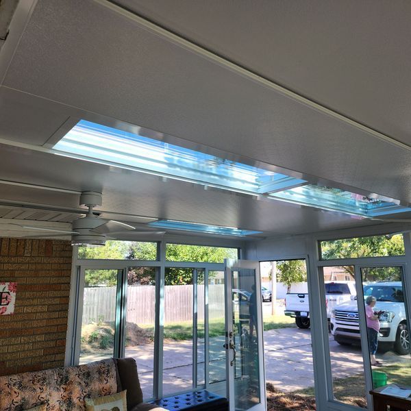Sunroom with glass windows and a skylight, showing a view to the outside.