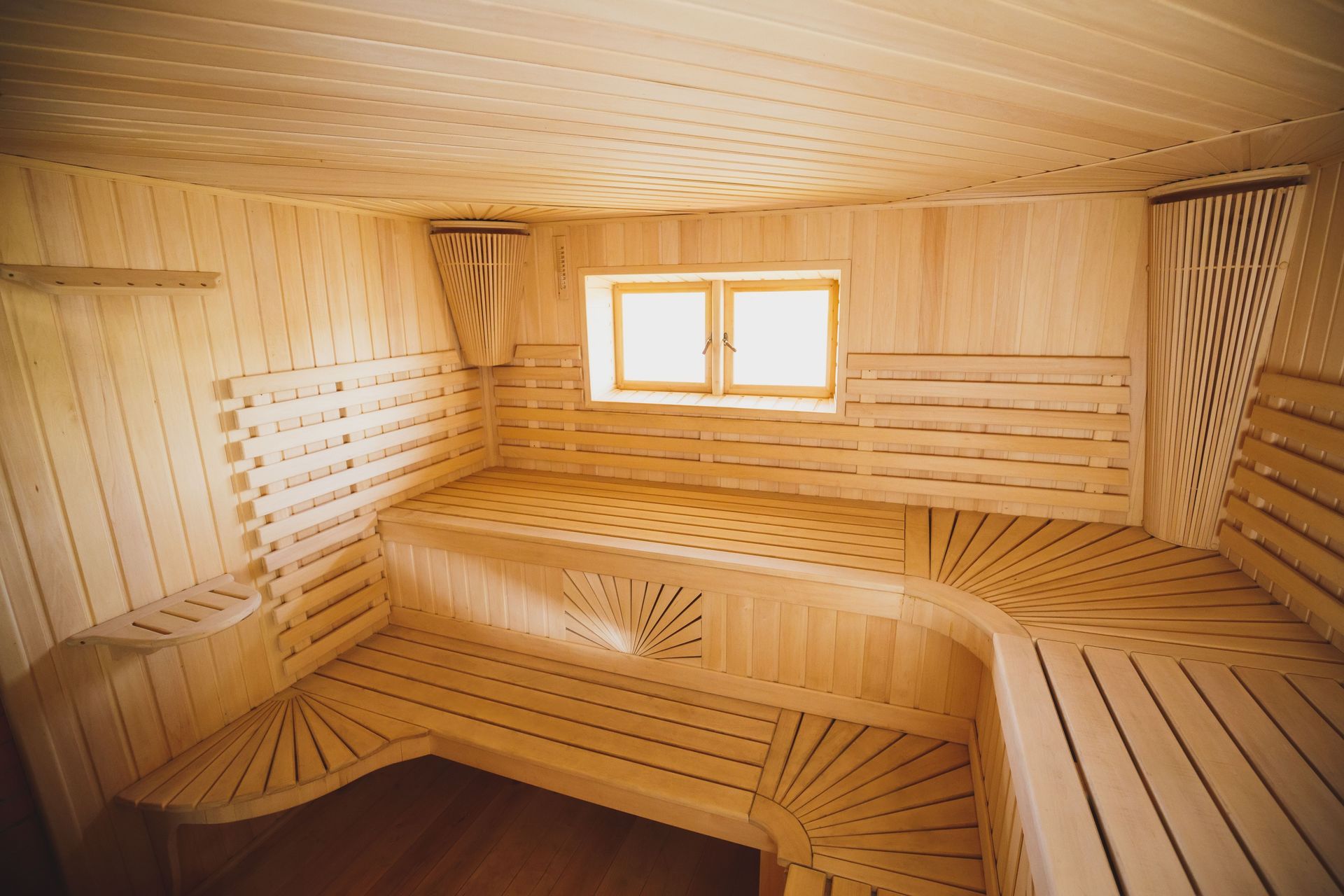 Wooden sauna interior with slatted benches and a small window.