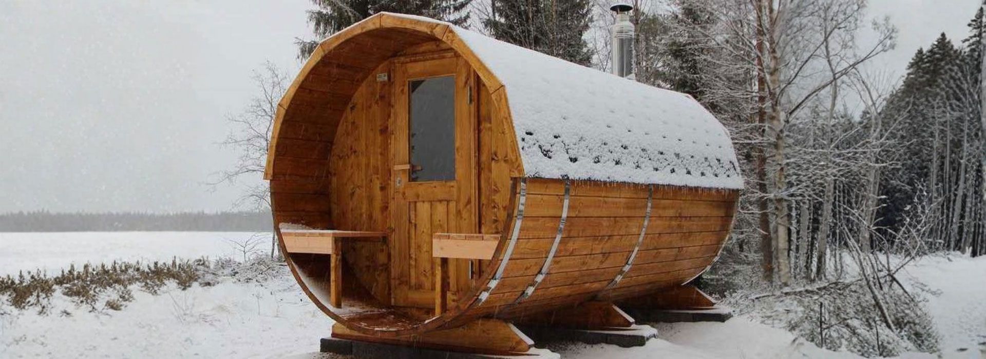 Wooden barrel sauna in a snowy landscape.