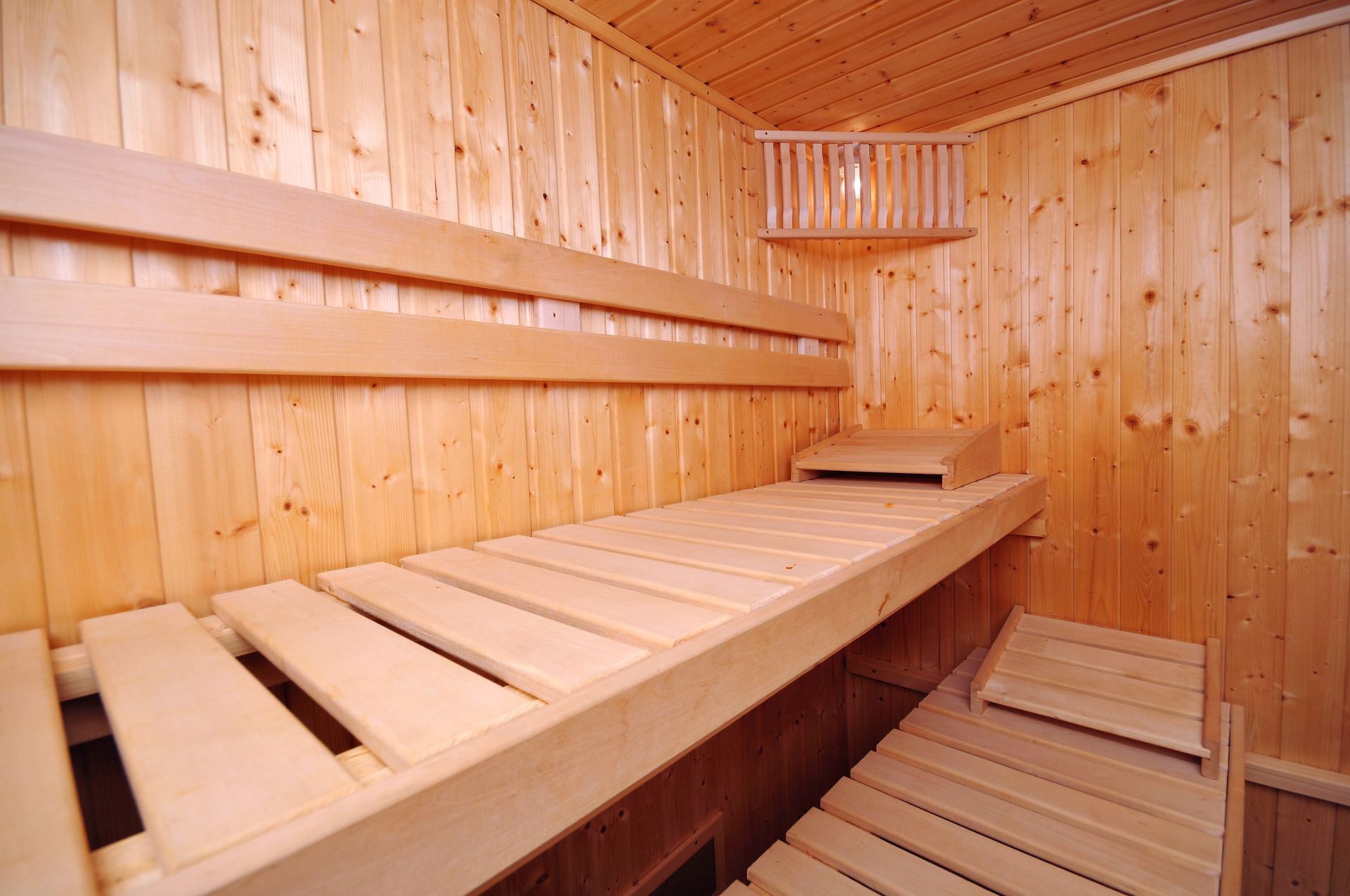 Wooden sauna interior with benches, walls, and a small shelf.