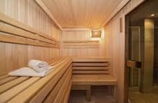Wooden sauna interior with benches, towel, and glass door.