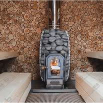 Sauna with wood-burning stove and stone-lined walls. Benches are visible.