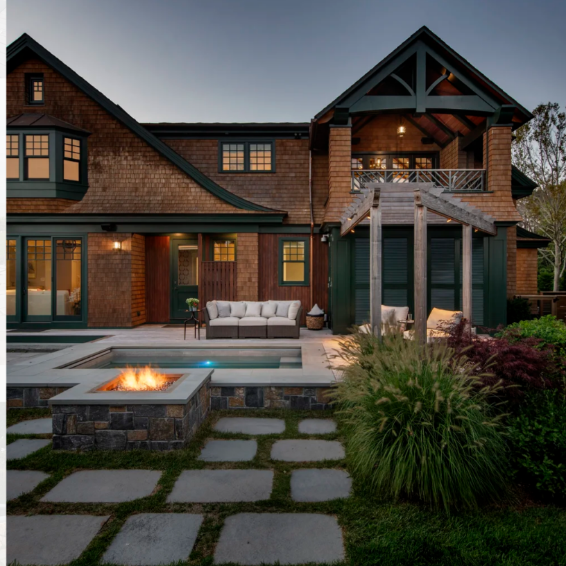 Backyard with pool, fire pit, and seating in front of a wood-shingled house.