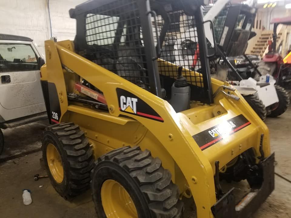 A yellow cat skid steer is parked in a garage.