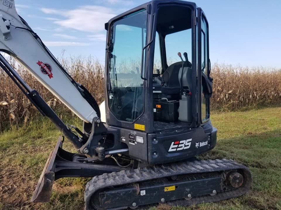 A bobcat excavator is parked in a grassy field