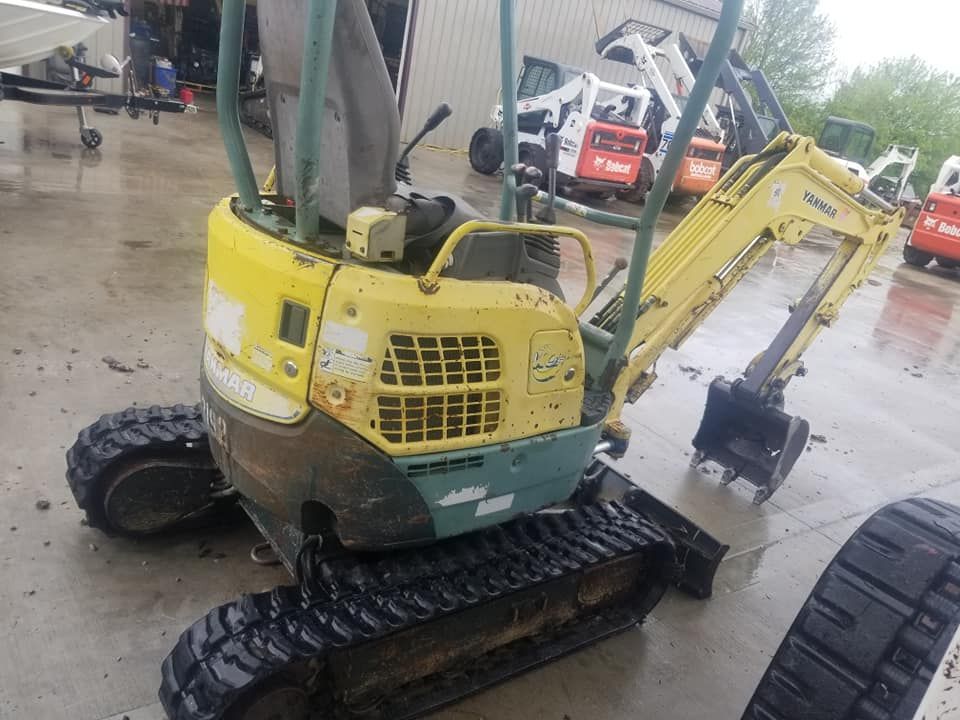 A small yellow excavator is parked in a parking lot.