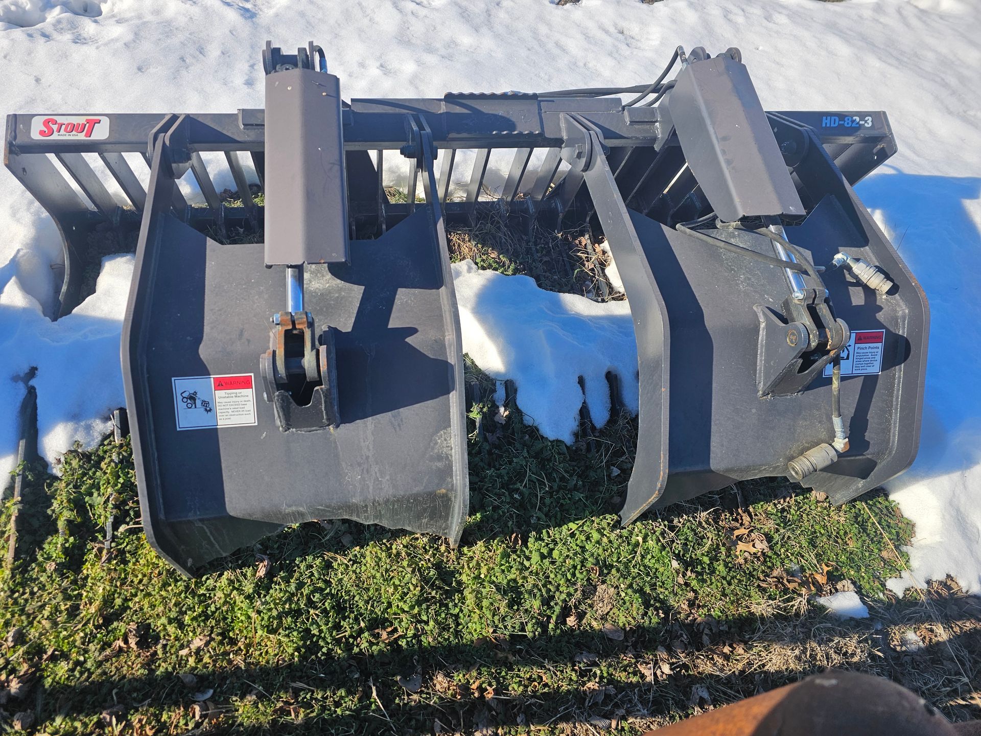 A tractor is sitting in the snow with a bucket attached to it