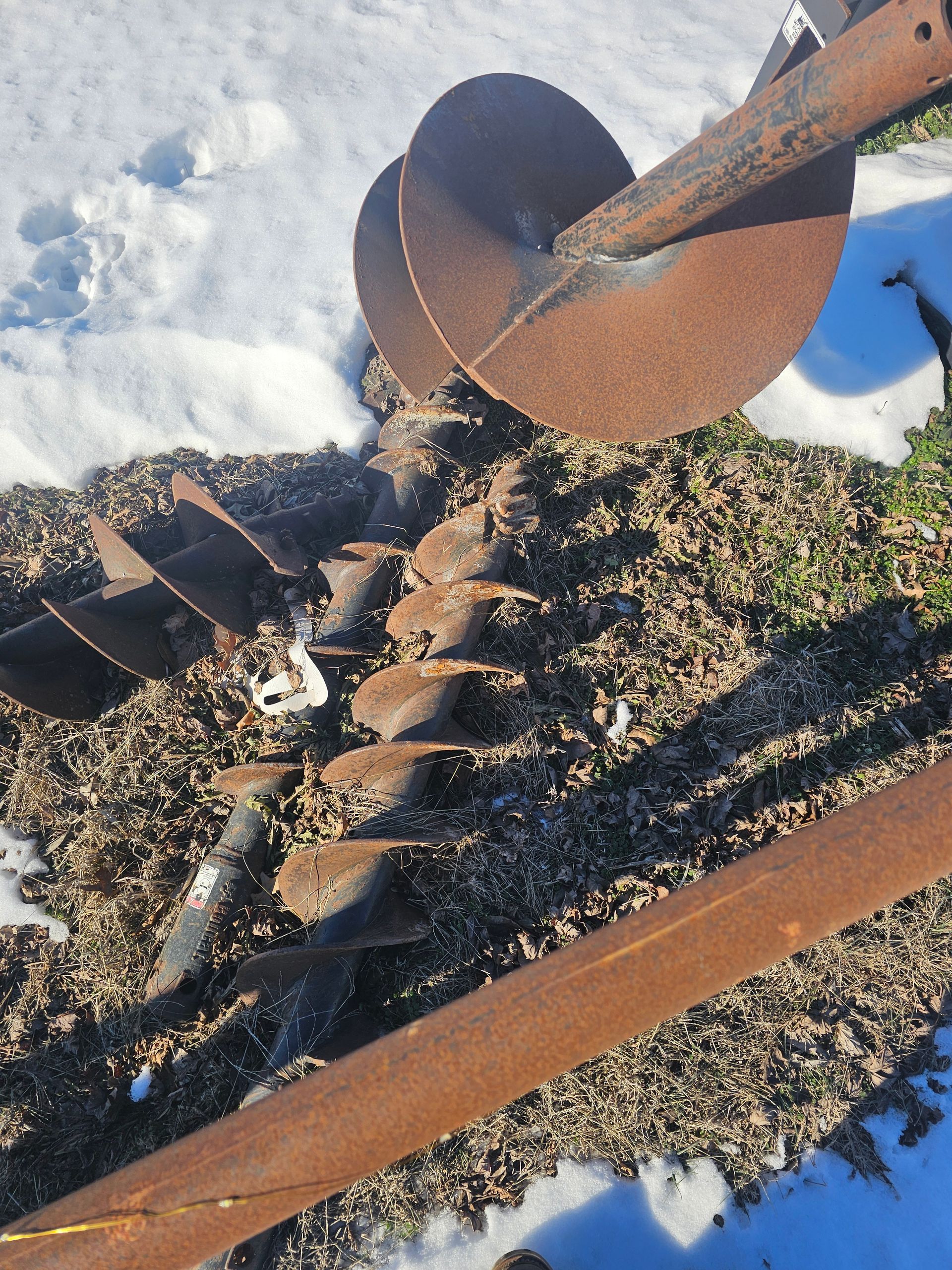 A rusty drill bit is sitting on a pile of gravel