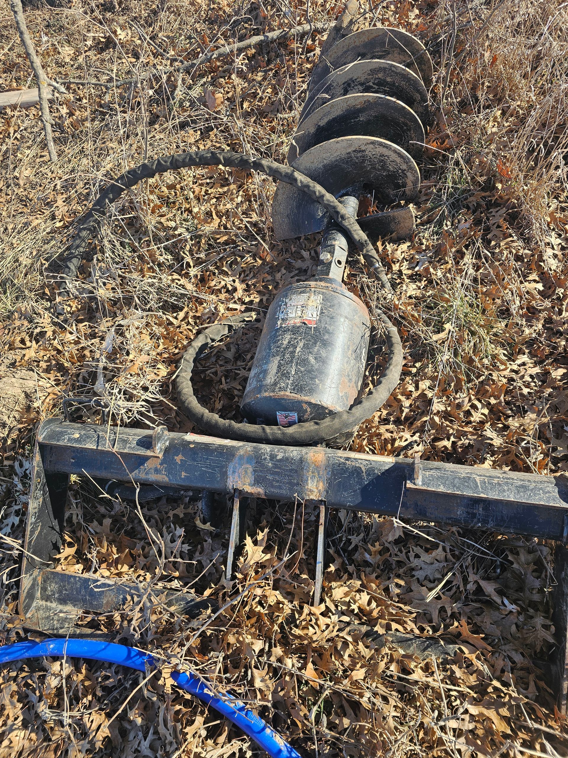 A drill bit is sitting on top of a pile of leaves.