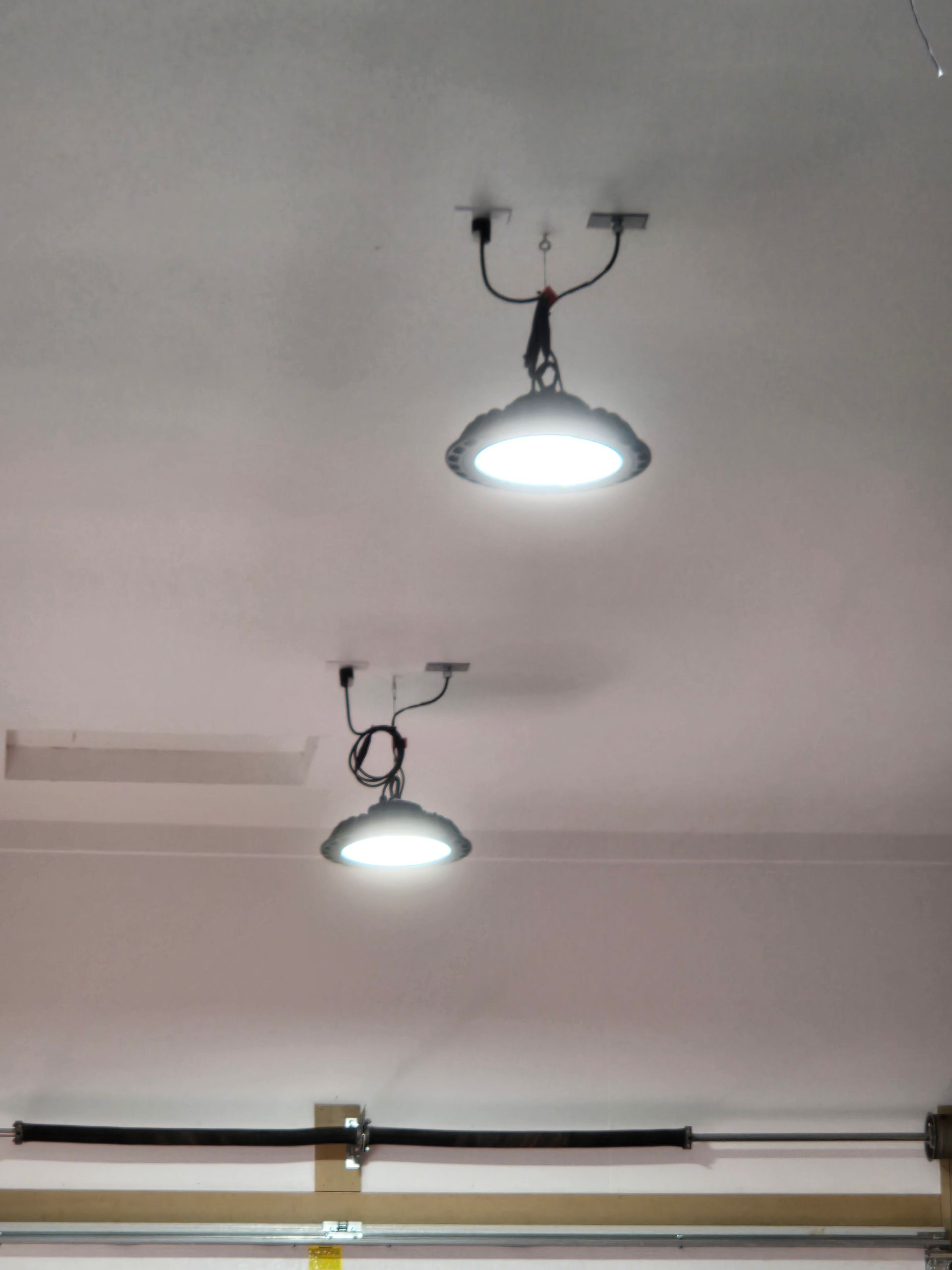 Two ceiling lights glowing on a white ceiling in a room.
