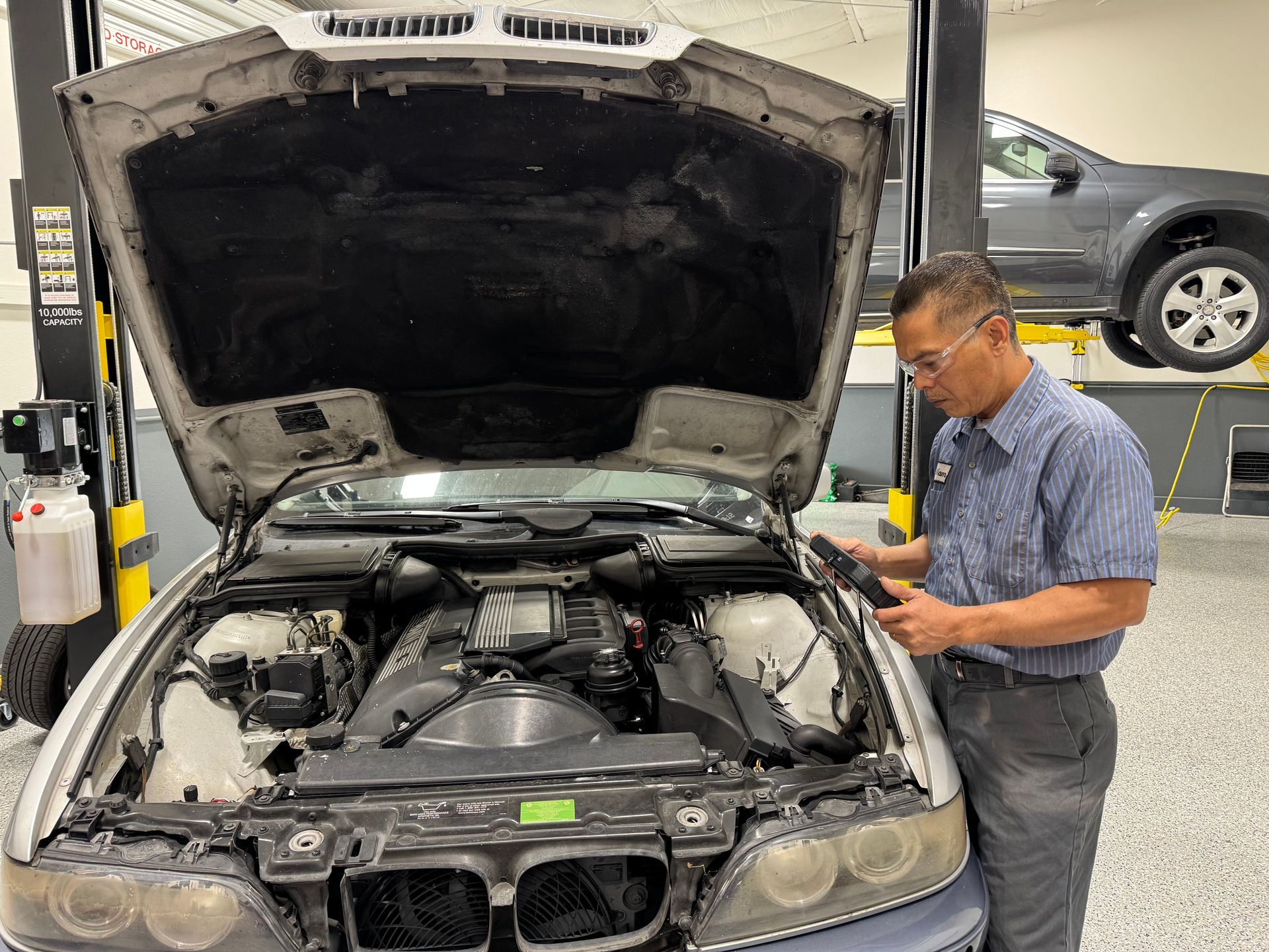 A man is looking under the hood of a car.