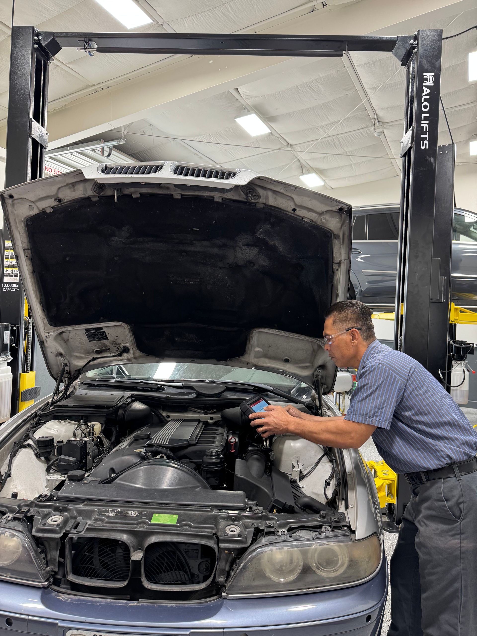 A man is working on the engine of a car in a garage.