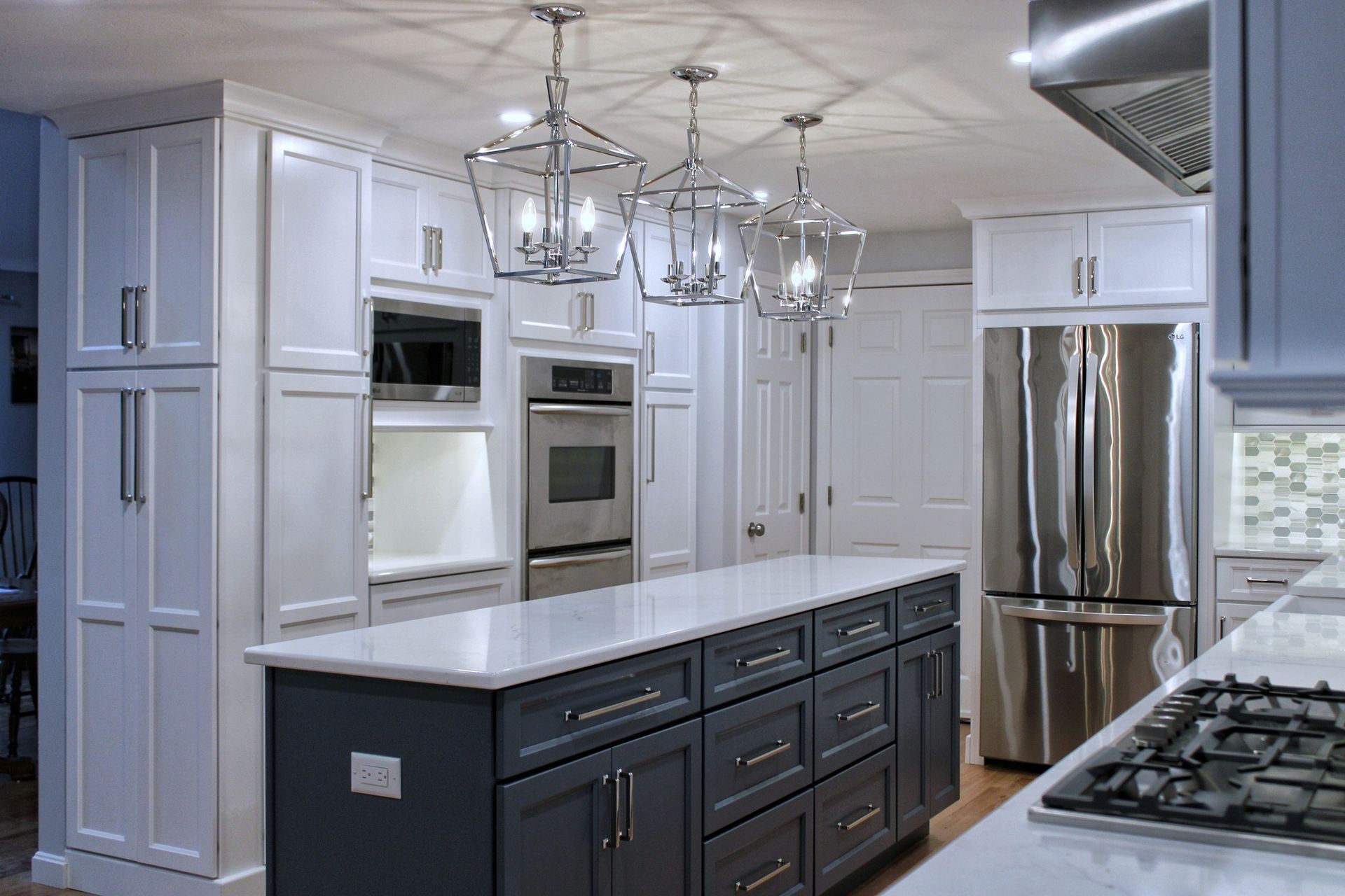 Modern kitchen with white and gray cabinets, stainless steel appliances, and a gray island with a white countertop.
