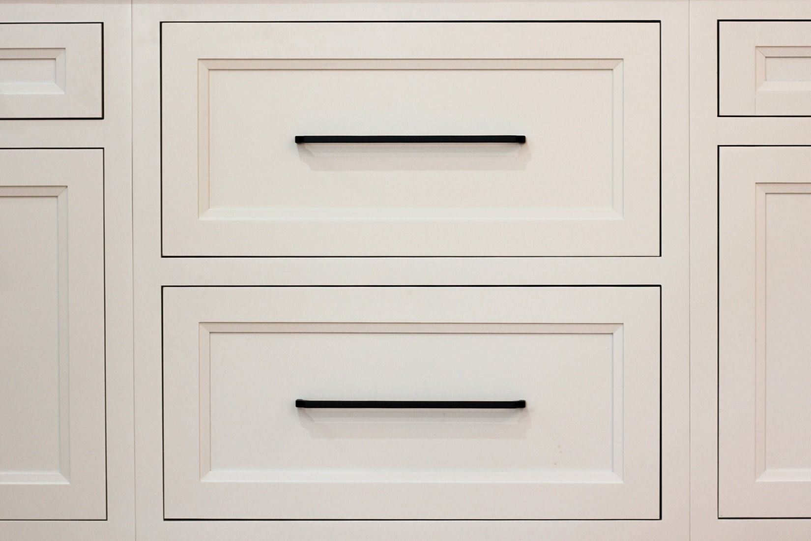 White cabinet with two drawers featuring black horizontal handles.