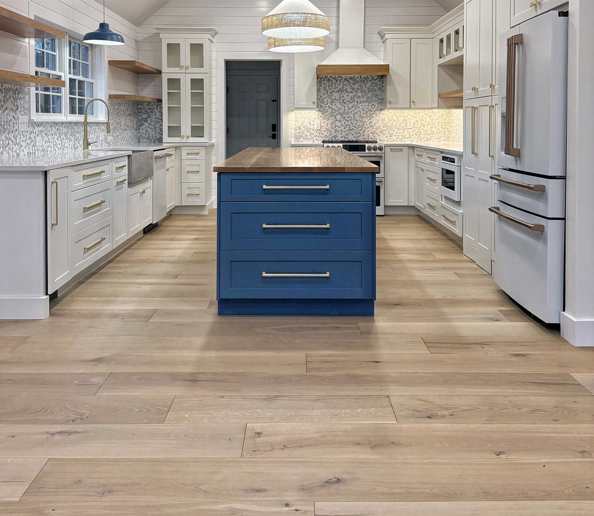 Kitchen with white cabinets, blue island, wood floors, and neutral backsplash.