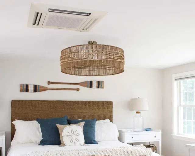 Bedroom with nautical decor: bed, ceiling air unit, pendant light, oars, and window.