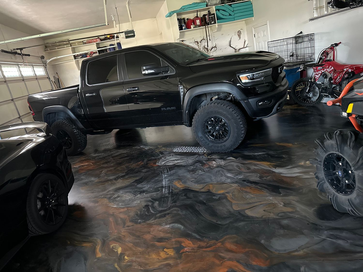 A black truck is parked in a garage next to a motorcycle.
