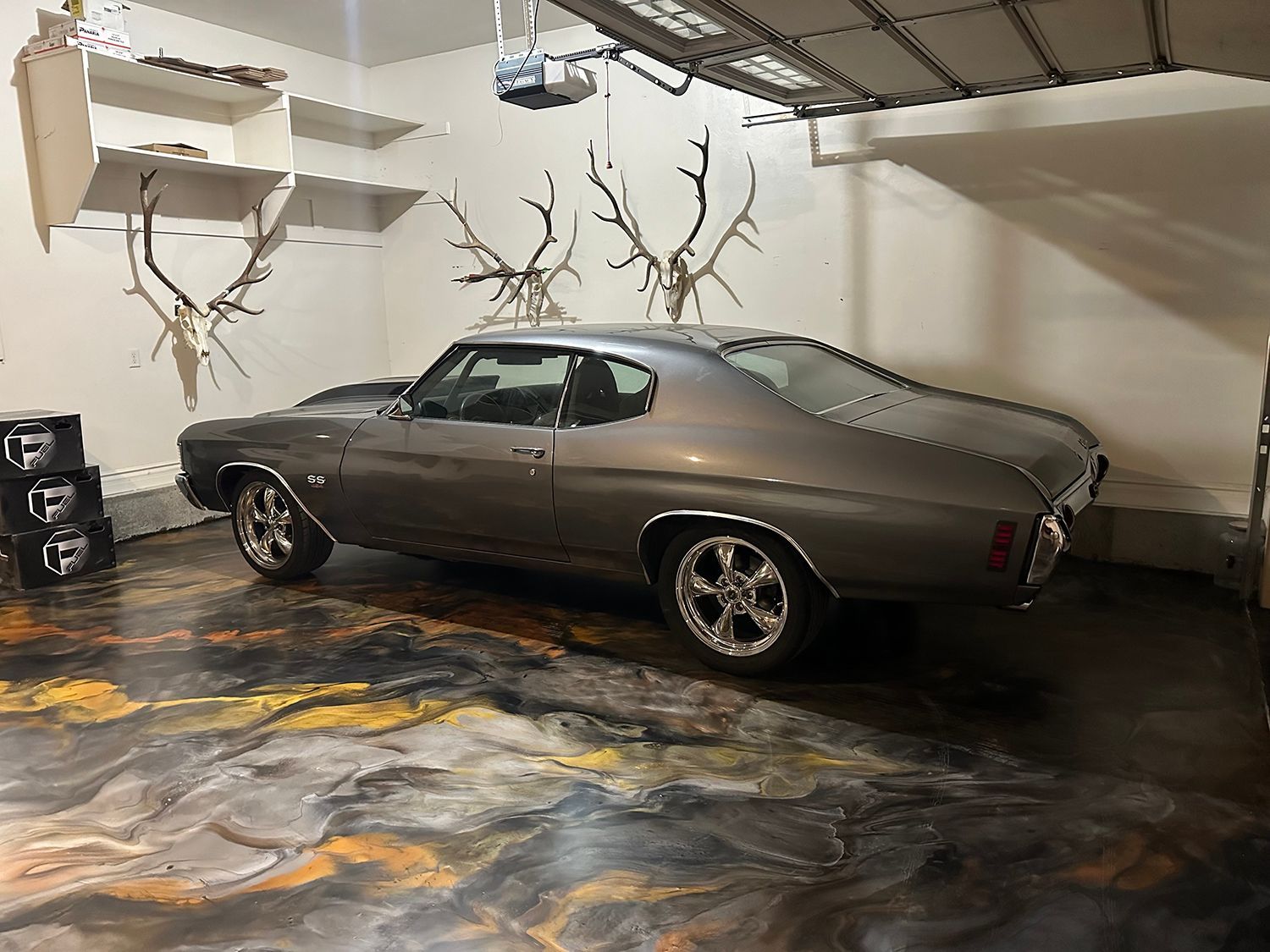 A car is parked in a garage with deer antlers on the wall.