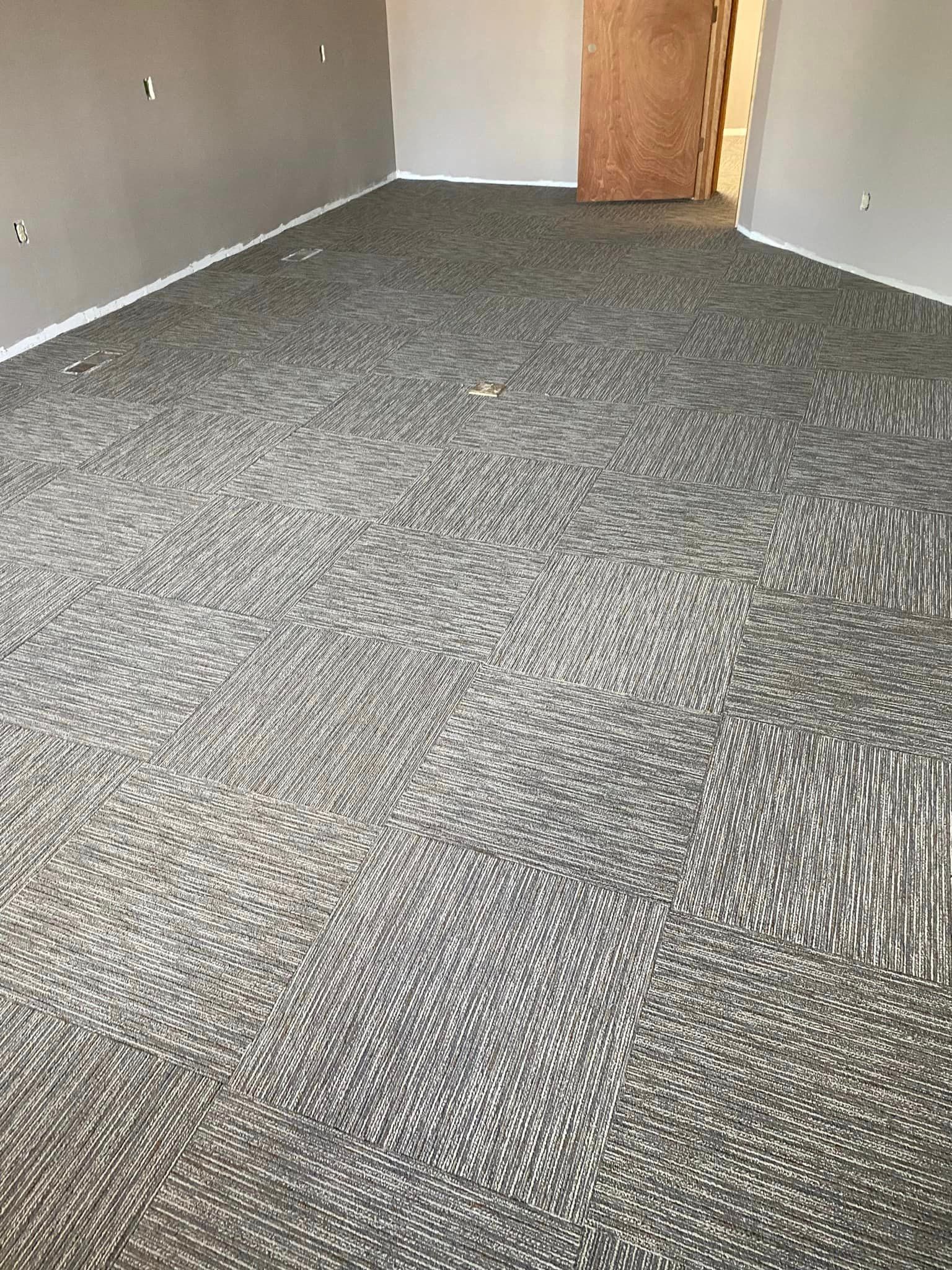 A large room with a carpeted floor and a door.