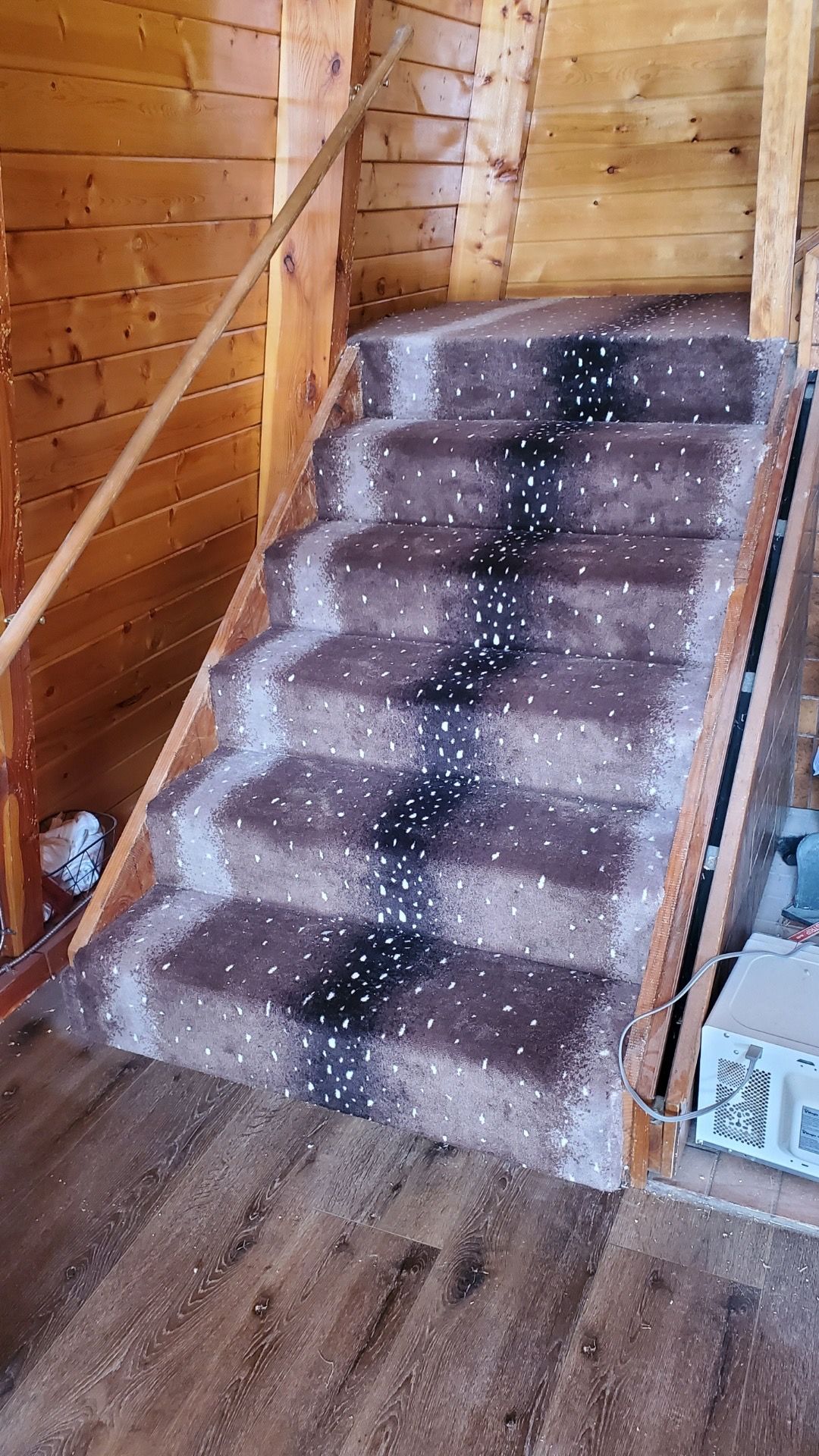 A staircase with a wooden railing and a carpeted staircase in a wooden house.