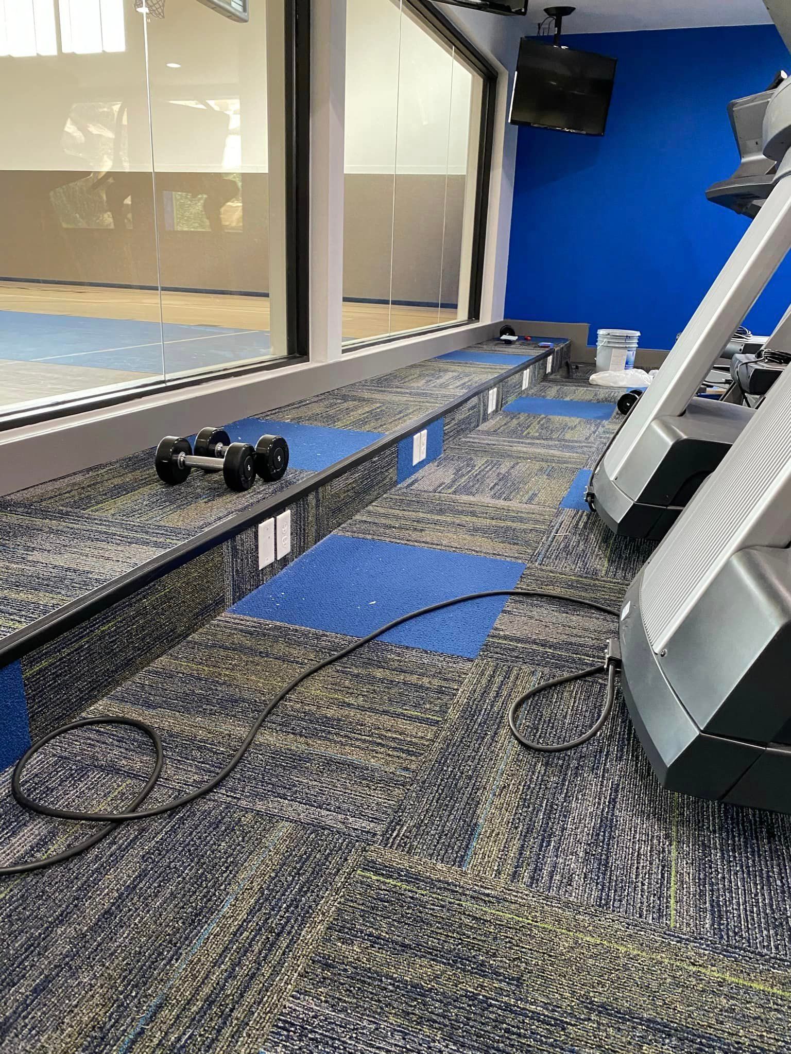 A gym with a treadmill , dumbbells , and a mirror.