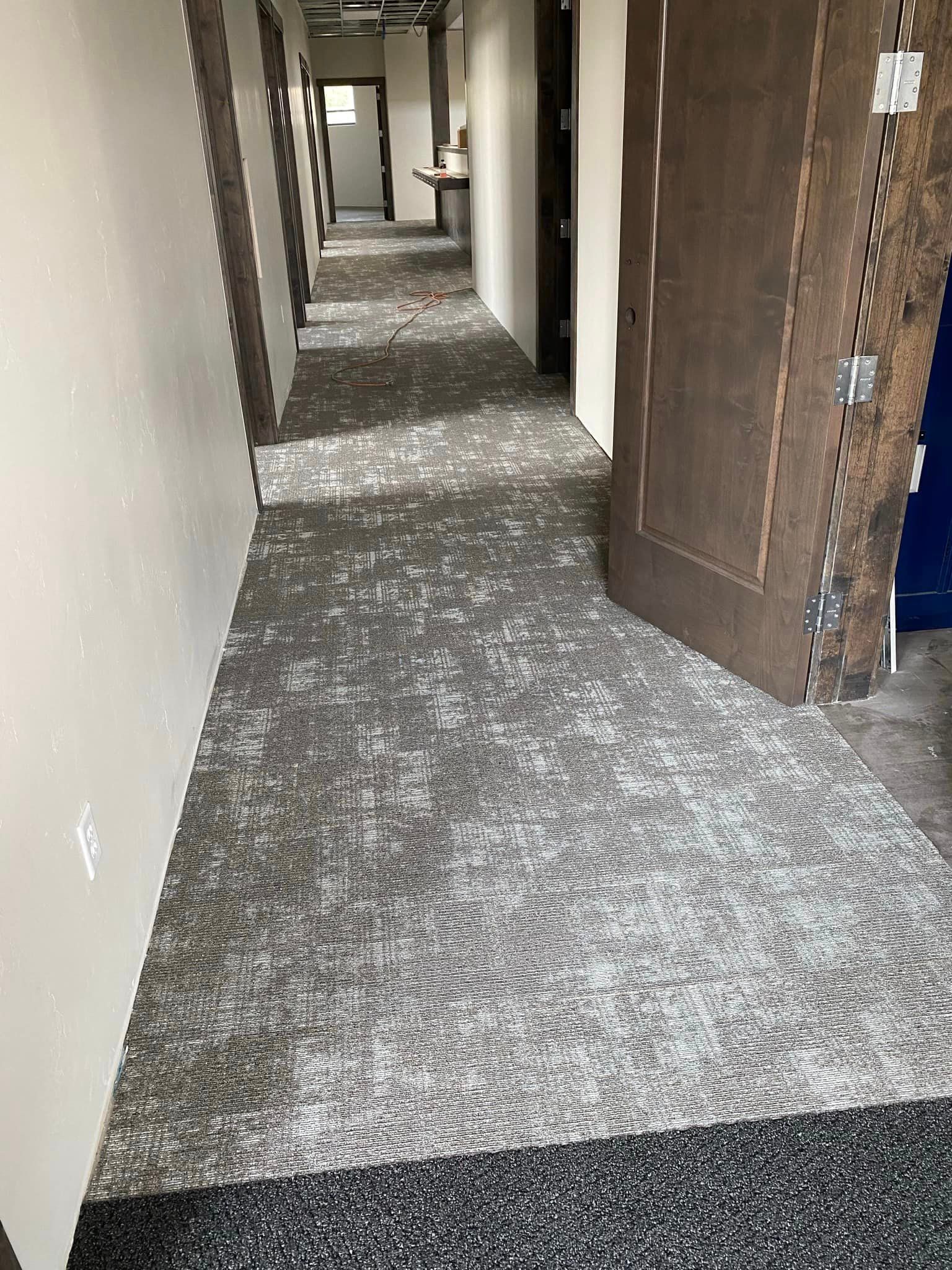 A long hallway with a carpeted floor and a door.