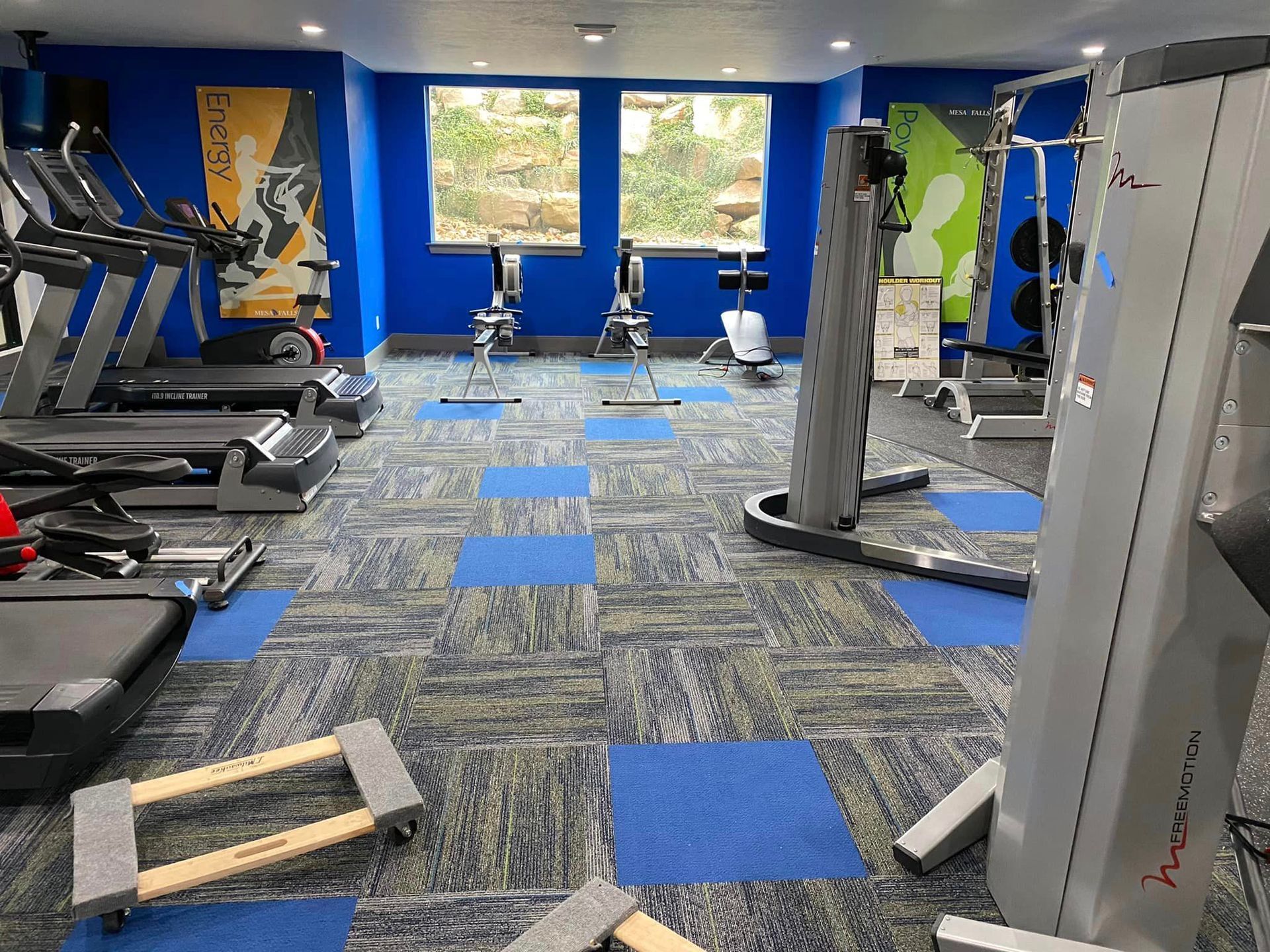 A gym with a lot of equipment and a blue wall.